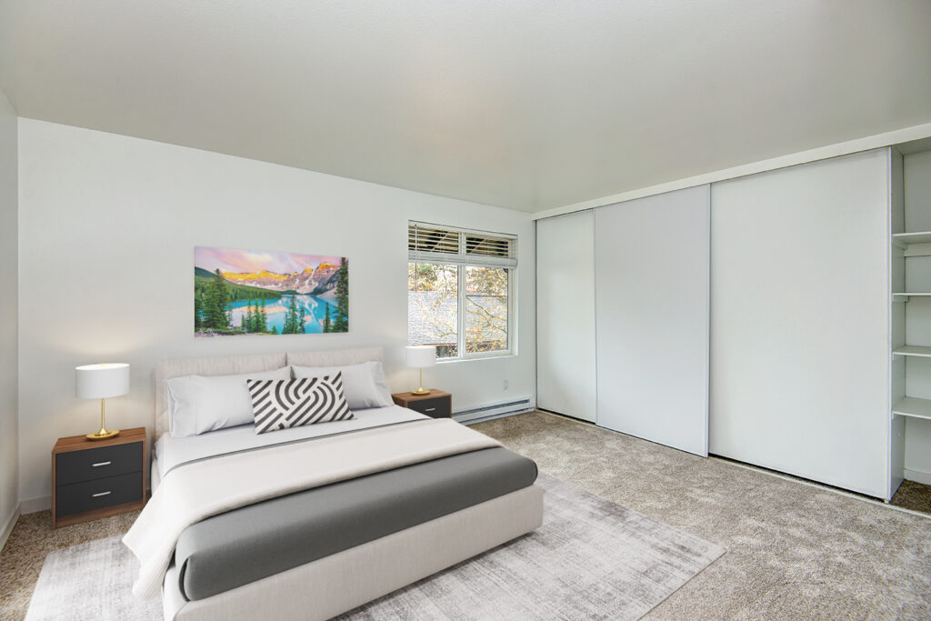 Carpeted bedroom with sliding closet doors and built in shelves in our apartments for rent in Everett, WA.