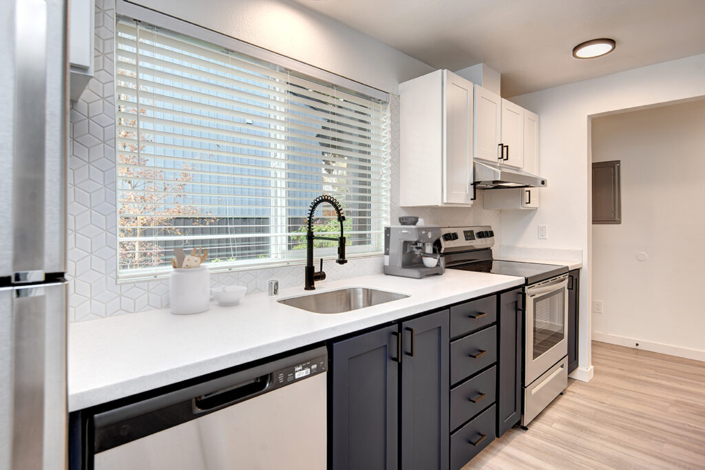 Kitchen with white counters and stainless steel appliances at our apartments in Everett, WA." " Kitchen with white counters and stainless steel appliances